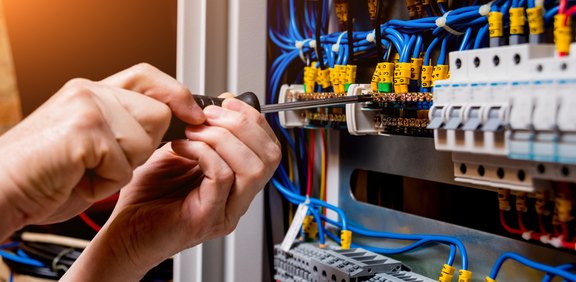 Elektriker arbeitet mit Schraubendreher in einem Schaltschrank