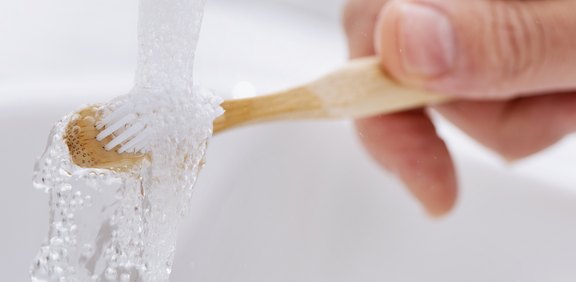 Zahnbürste wird unter fließendem Wasser abgespült