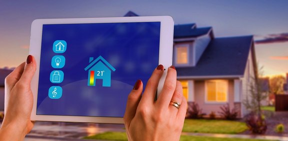 Tablet mit Smart-Home-Steuerung vor einem Wohnhaus