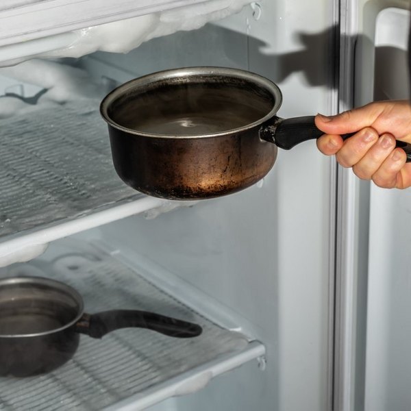 Topf mit heißem Wasser im vereisten Gefrierschrank