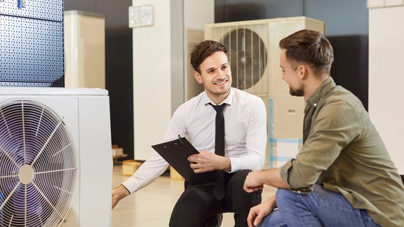Beratung zu modernen Heizsystemen: Wärmepumpe als zukunftssichere Lösung Fachberater erklärt einem Kunden die Vorteile einer modernen Wärmepumpe als Heizsystem.