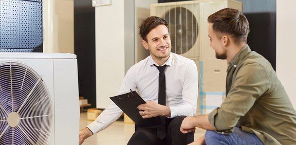 Fachberater erklärt einem Kunden die Vorteile einer modernen Wärmepumpe als Heizsystem.