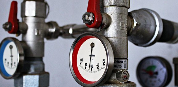 Heizungsrohre mit Thermometern und roten/blauen Ventilen