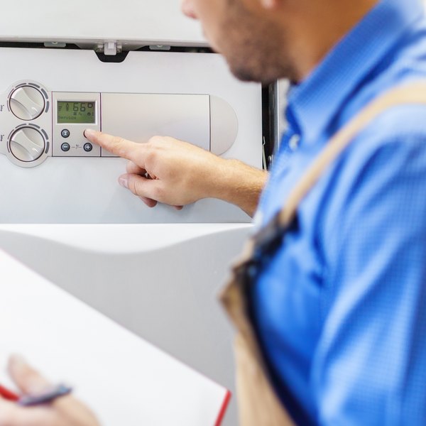 Monteur stellt die Regelung einer Heiztherme ein