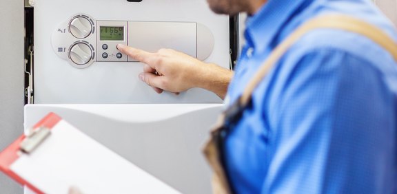 Monteur stellt die Regelung einer Heiztherme ein