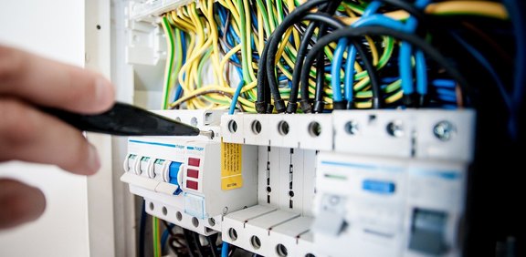 Hand schaltet Sicherung im Elektroverteiler