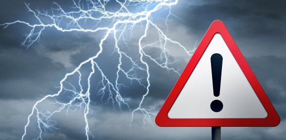 Gewitterhimmel mit Blitzen und Warnschild.